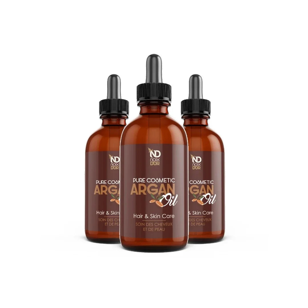 Three amber glass bottles of Noix d'Or Pure Cosmetic Argan Oil for hair and skin care.
